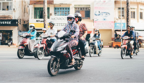Several people riding motor scooters down a street