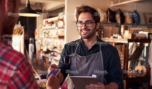 Young man working in a shop being handed a credit card.